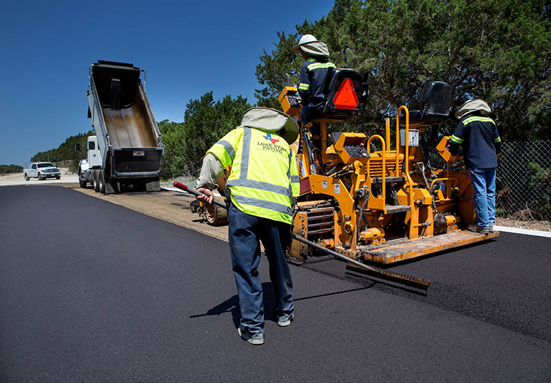 Back of crew member spreading asphalt